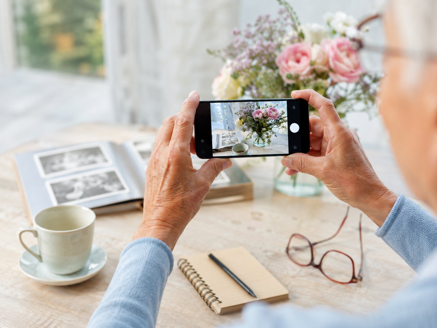 &Auml;ltere H&auml;nde halten ein Smartphone und nehmen ein Foto auf.